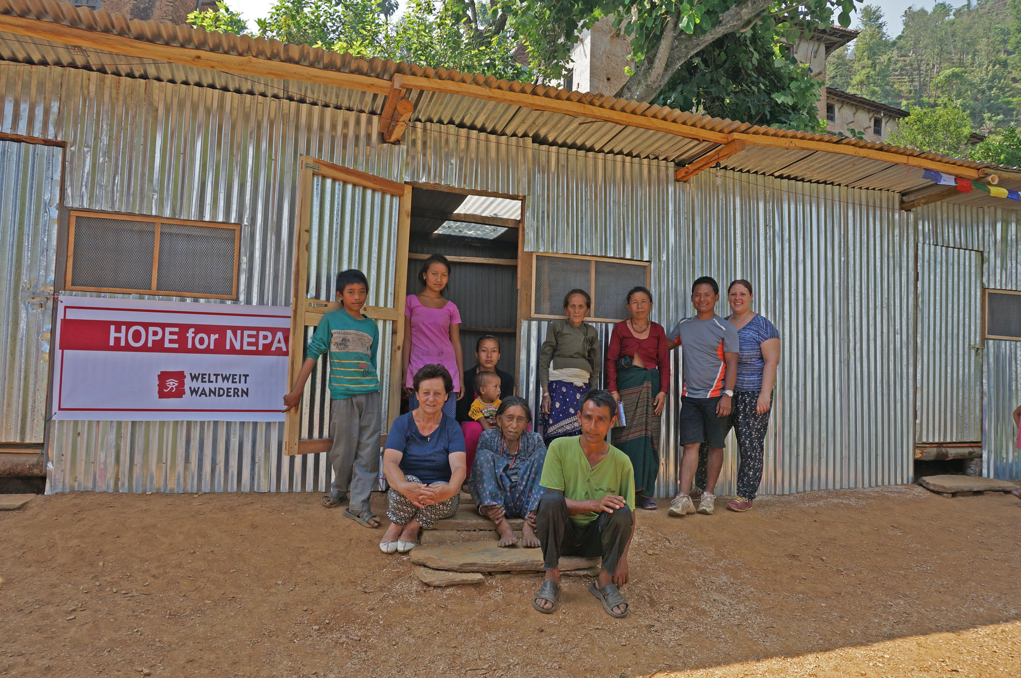 Sandra Pieber, ihre Familie und Dorfbewohner vor einer der neu errichteten Hütten.